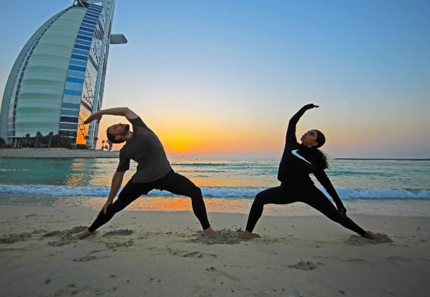 Couples doing yoga on the beach nearby Burj Al Arab