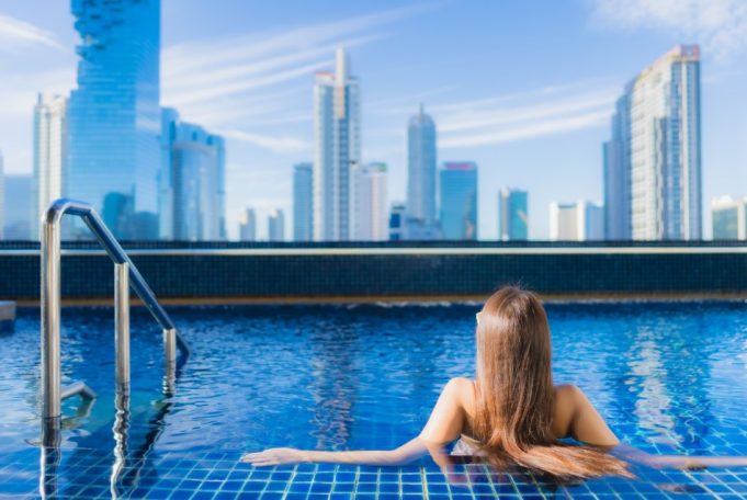 Woman in the pool looking at city skyline